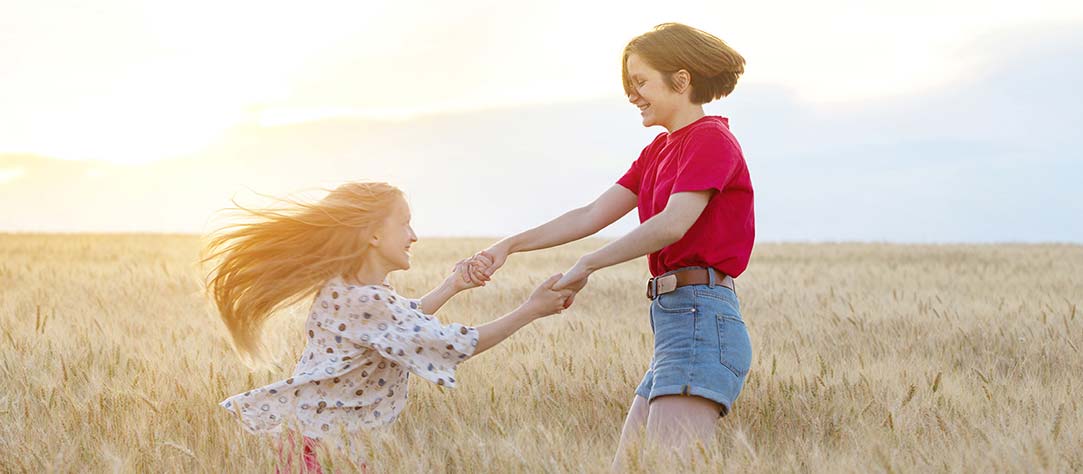 A young girl and teen dancing in a wheat field
